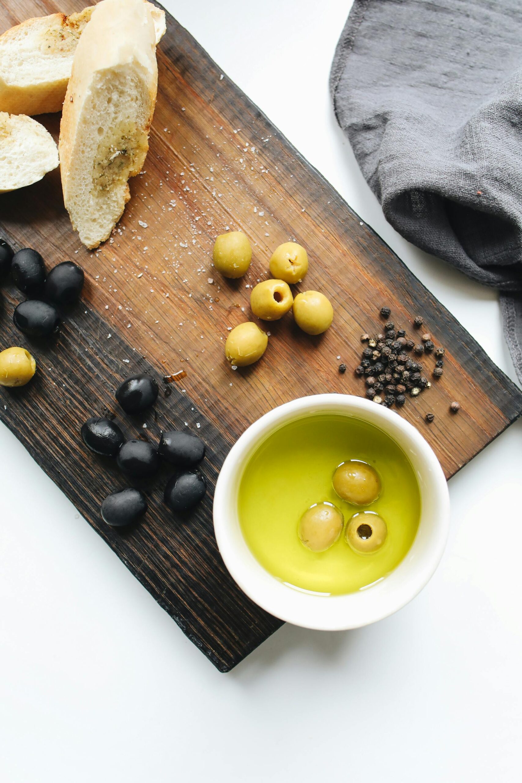 Rustic wooden board with fresh olives, bread, and olive oil. Perfect for culinary themes.